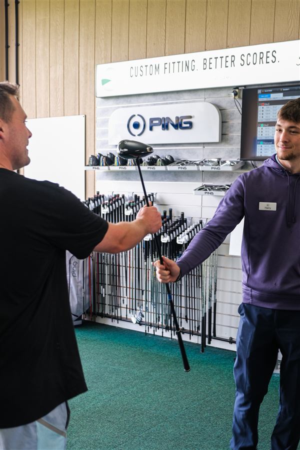 Fitting technician handing a customer a driver to test at Winchester Golf Academy