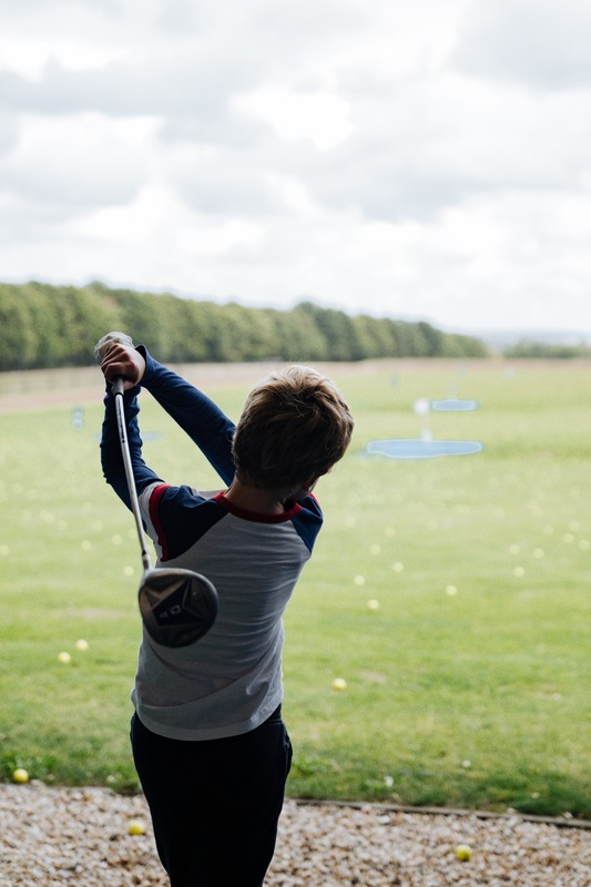 A young junior golfer following through on a swing at Winchester Golf Academy