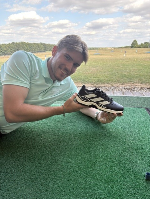 Toby holding the new adidas Codechaos golf shoe in a bay at Winchester Golf Academy