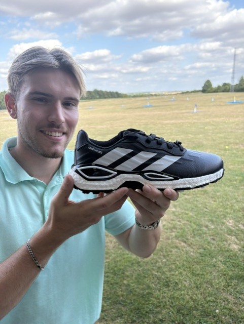 Close-up of the adidas Codechaos golf shoe held up on the range at Winchester Golf Academy